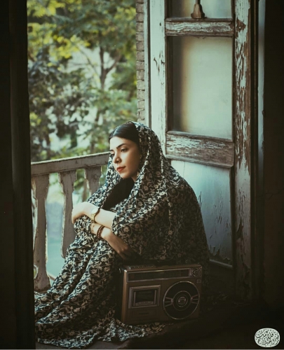 آخر خانم نشسته با چادر وموهای مشگی در خانه قدیمی وچوبی وحیاط